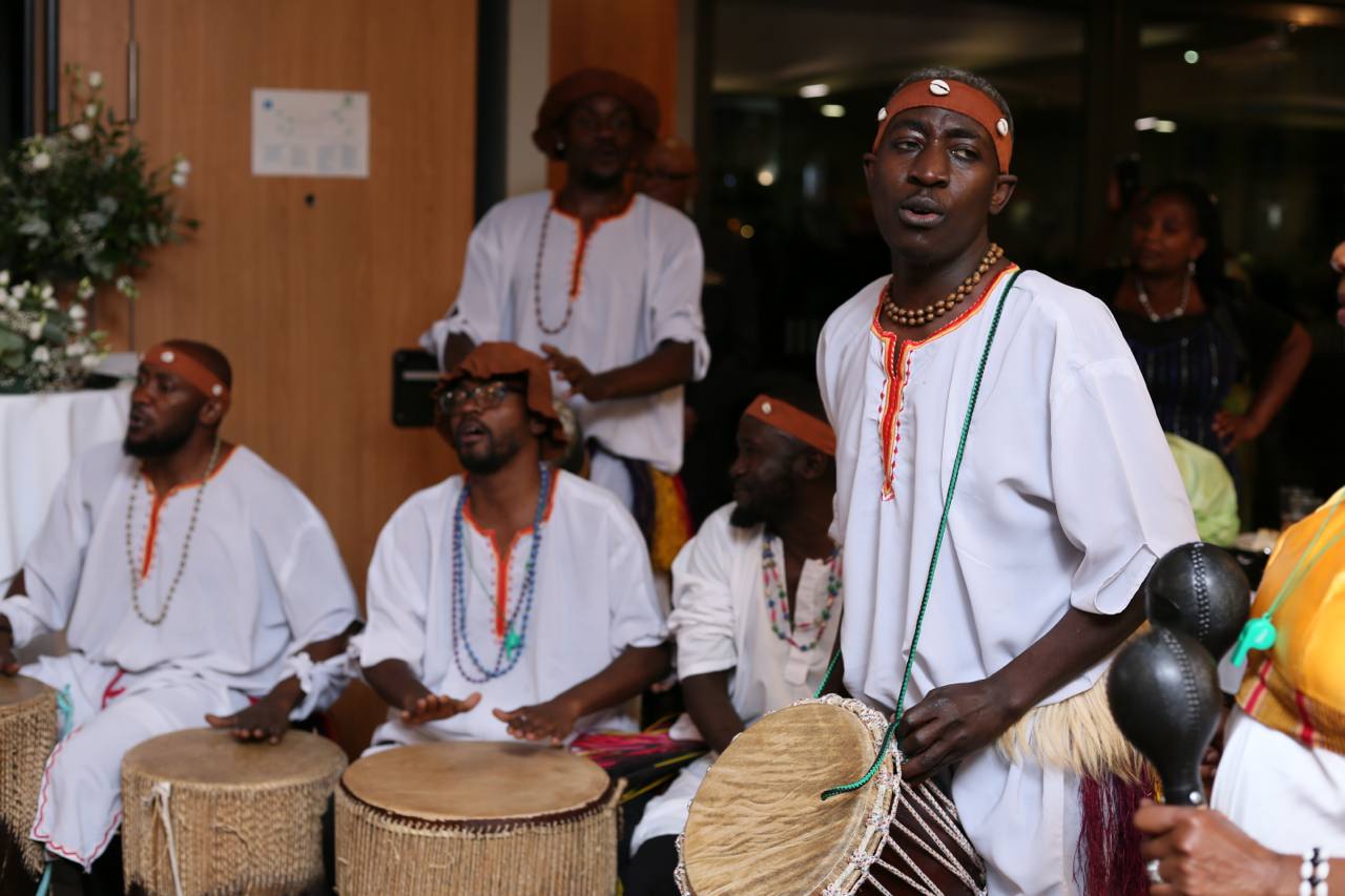 A group of men are playing drums in a room.