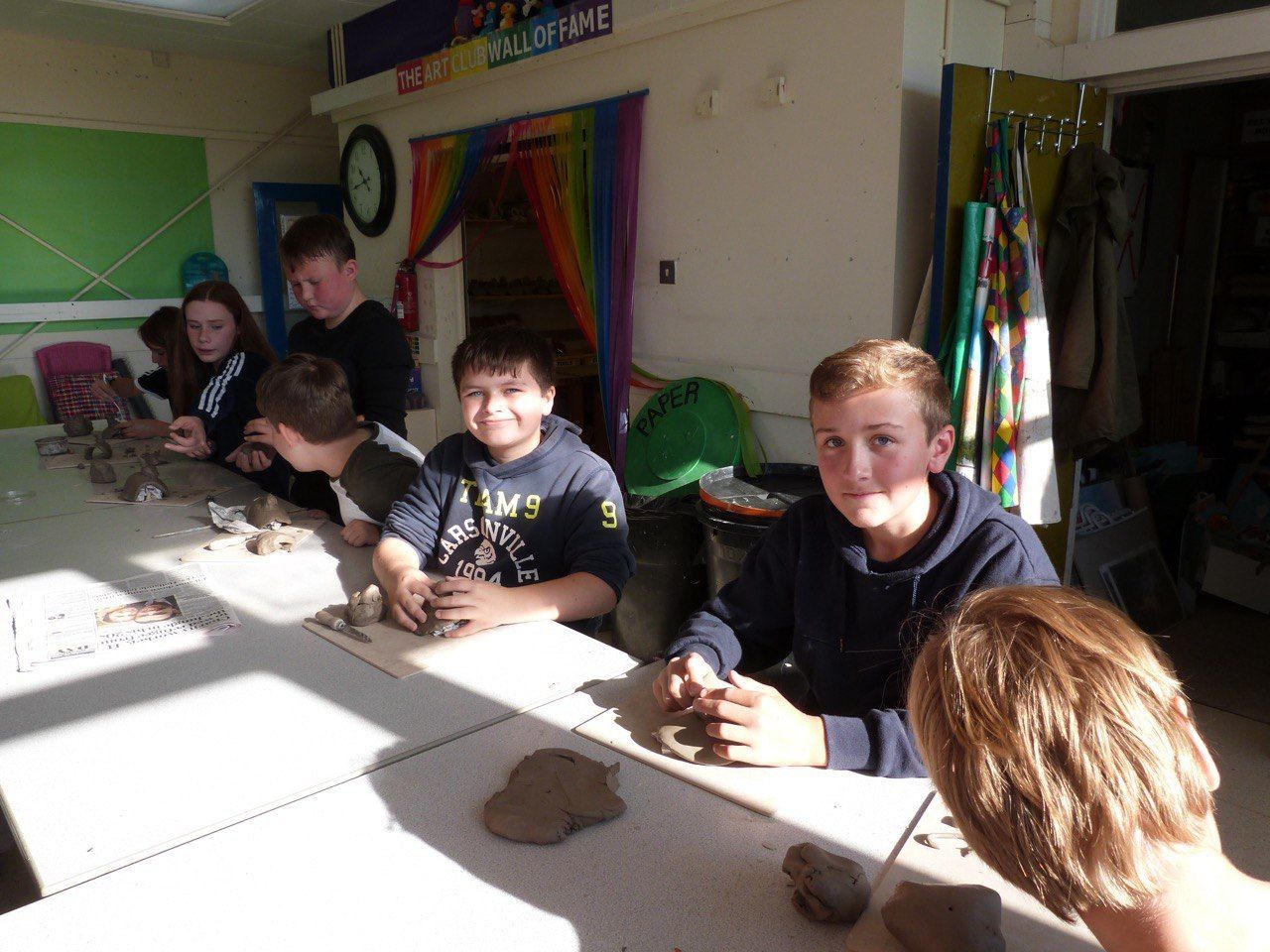 A group of children are sitting at a table with clay.