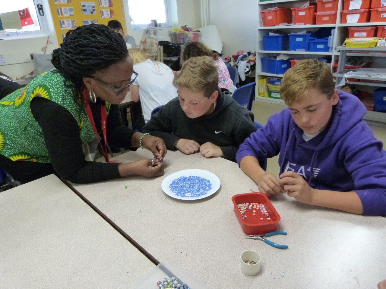 A group of children are sitting at a table playing with beads