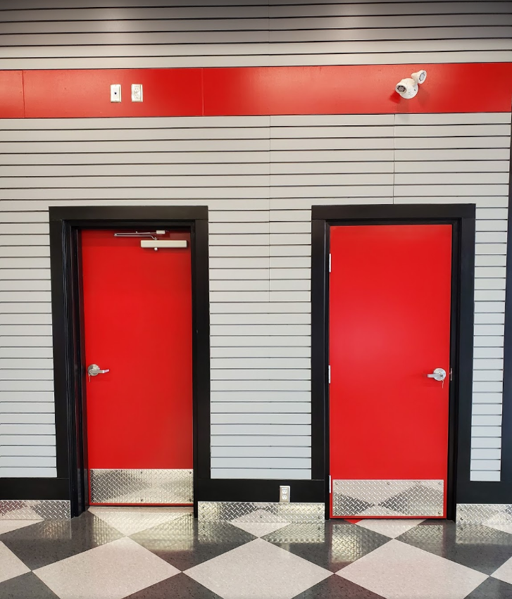 Two red doors in a room with a checkered floor