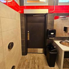 A bathroom with red brick walls and a black door