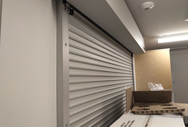 A white roller shutter is open in a room with boxes on the floor