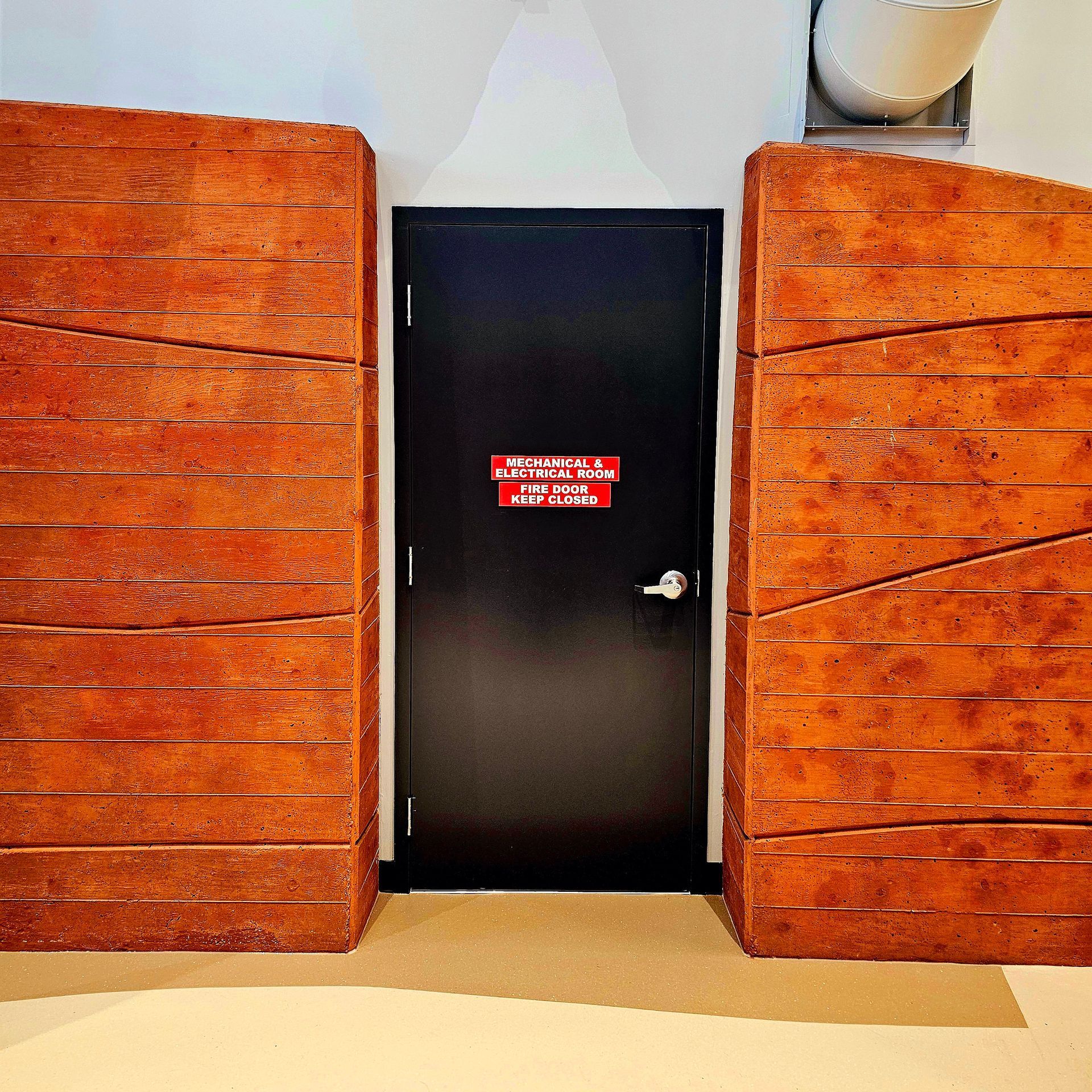 A black door with a red sign on it that says emergency exit