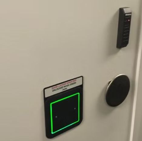 A close up of a door with a green light on it.
