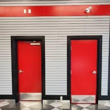 There are two red doors in a room with a checkered floor.