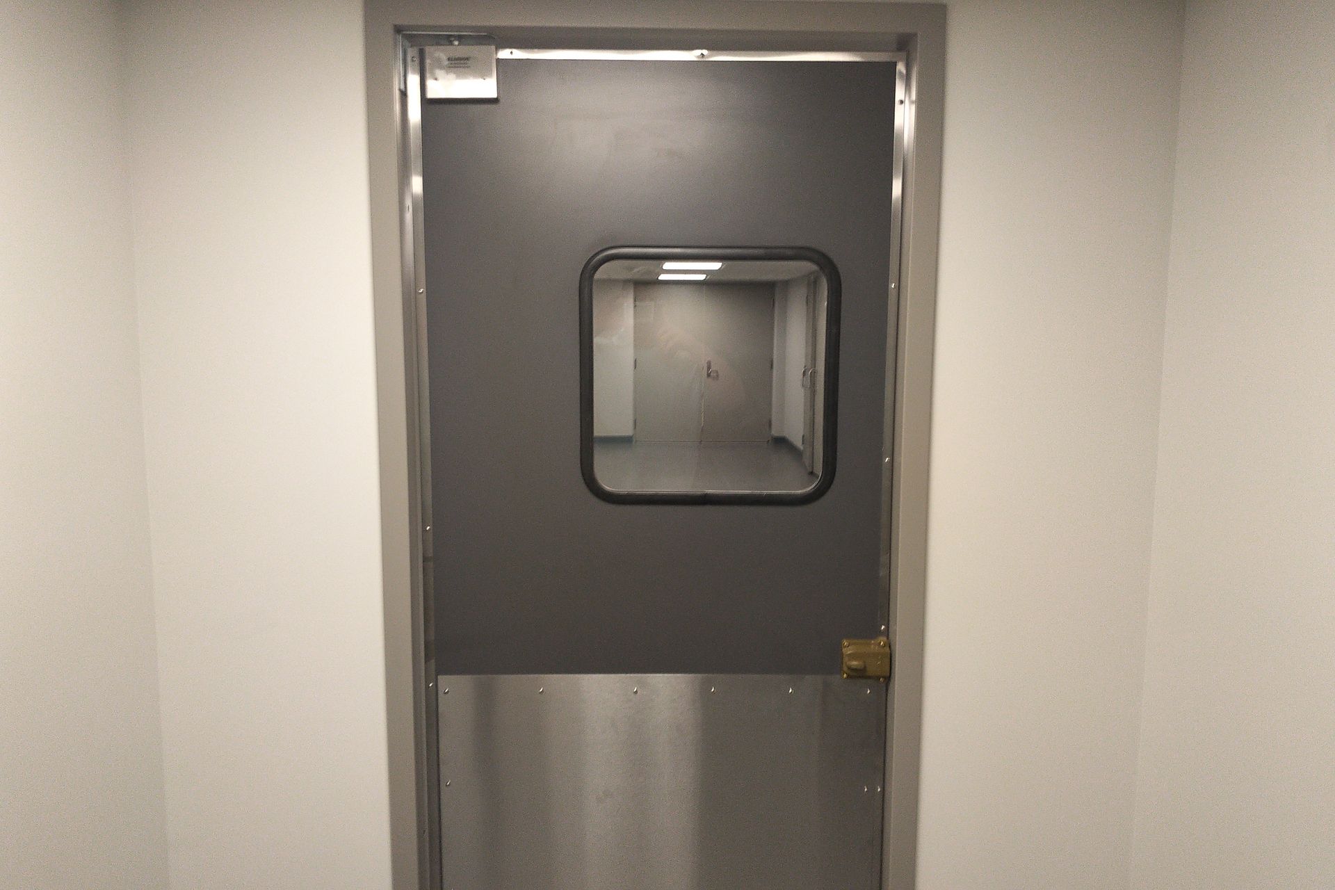 A stainless steel door with a window in a hallway.