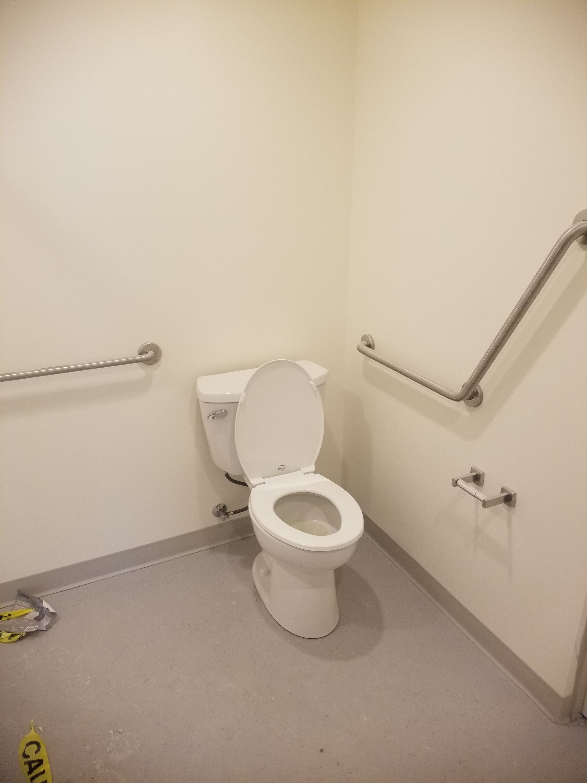 A toilet in a bathroom with a caution tape on the floor