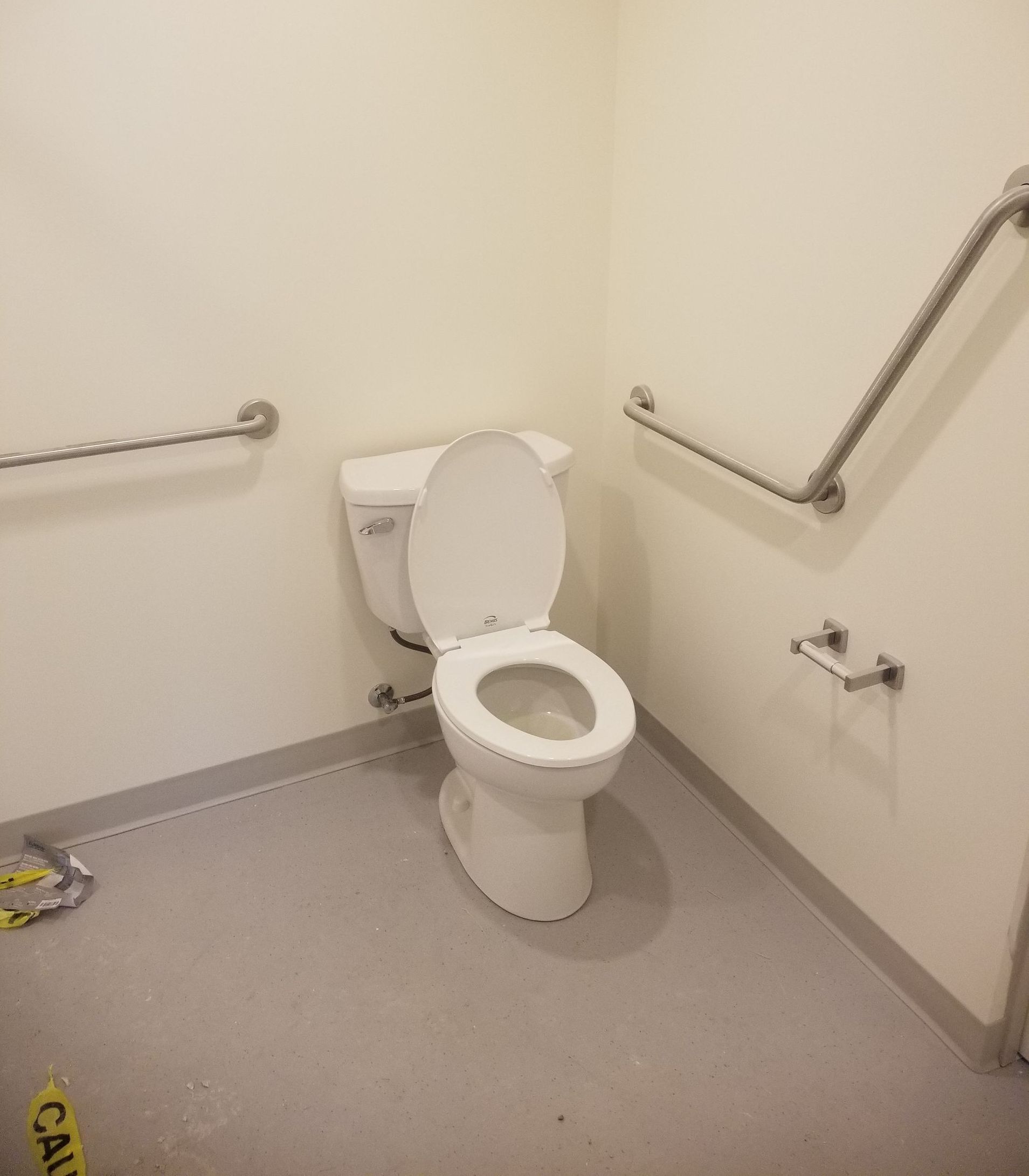 A toilet in a bathroom with a yellow caution tape on the floor