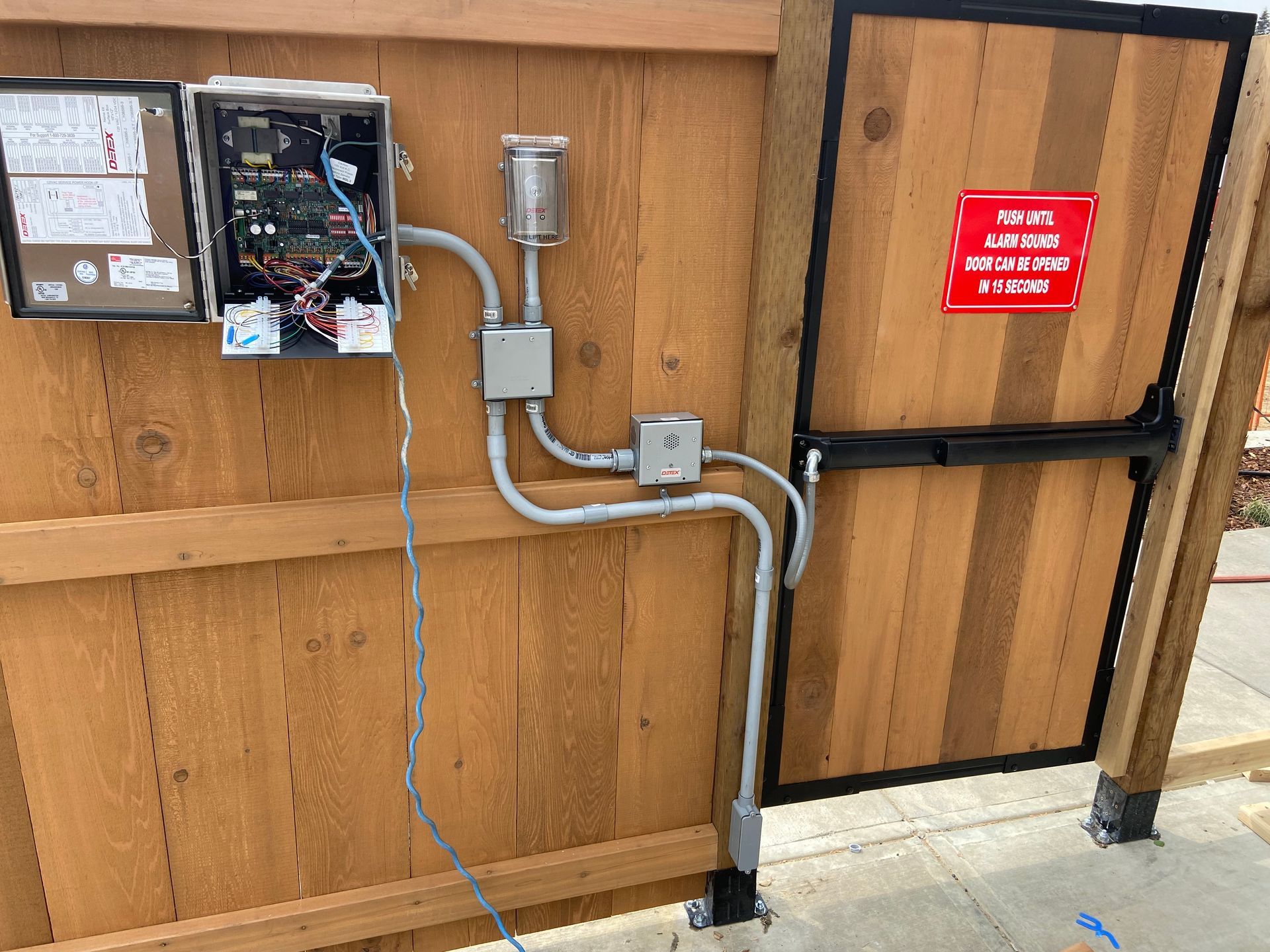 A wooden fence with electrical wires coming out of it.
