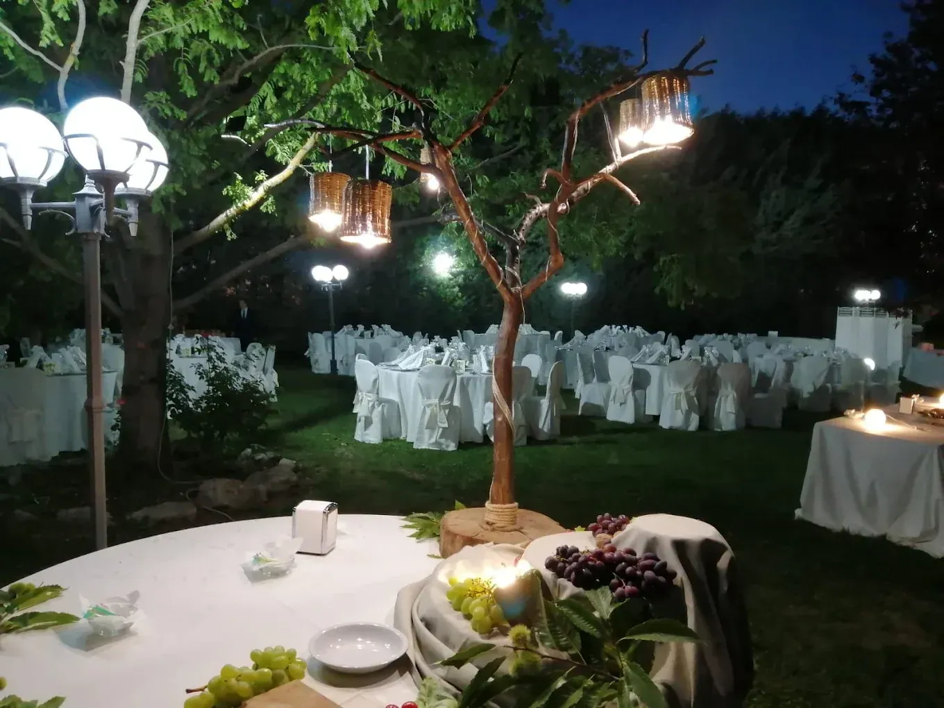 Ricevimento di nozze all'aperto con tavoli, luci e decorazioni notturne.