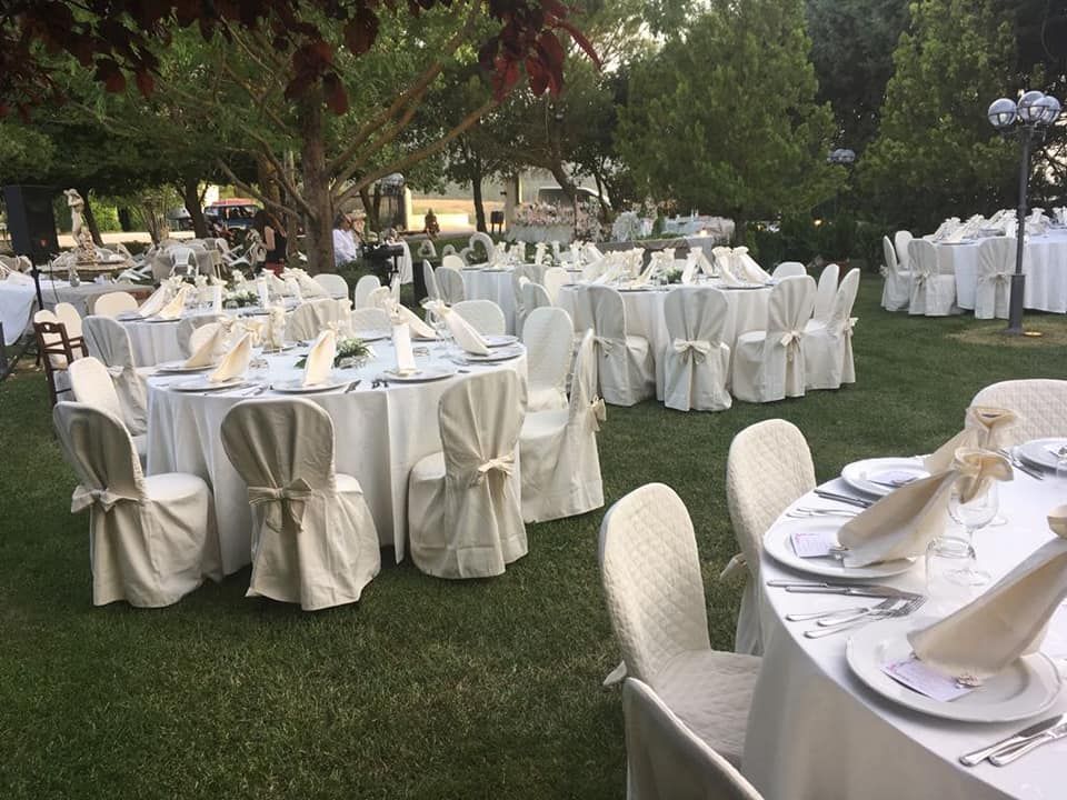 Ricevimento di nozze all'aperto con tavoli rotondi ricoperti di tovaglie bianche e sedie.