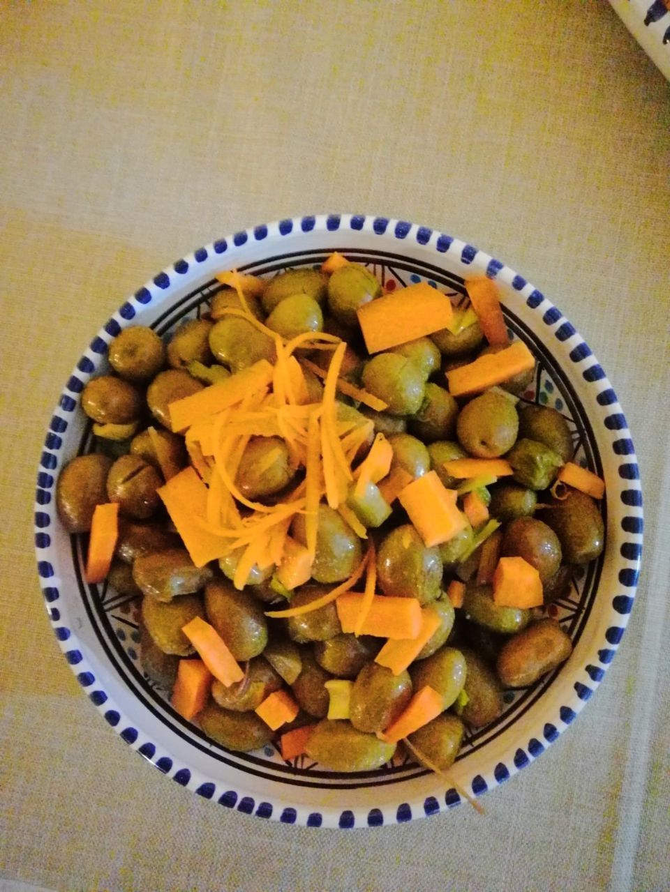 Ciotola di olive verdi e pezzi di carota, guarnita con julienne di carote.