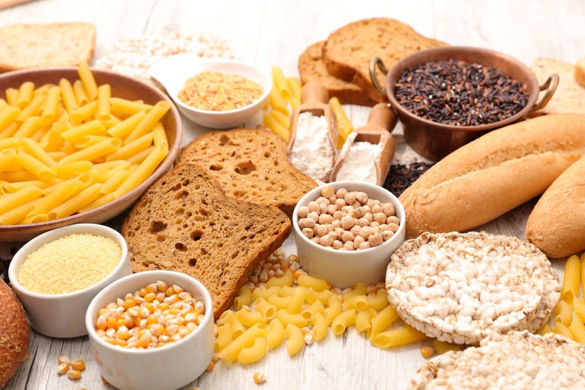 Assortimento di carboidrati: pasta, pane, gallette di riso, cereali e semi.