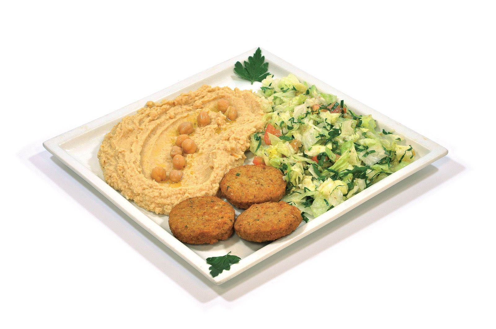 Un piatto quadrato bianco contenente una porzione di hummus, tre polpette di falafel fritte e un contorno di insalata verde tritata.