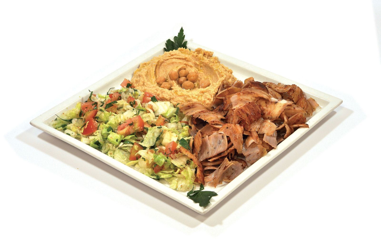 Un piatto quadrato bianco contenente una porzione di carne shawarma, un contorno di insalata fresca tritata e una cucchiaiata di hummus cremoso.