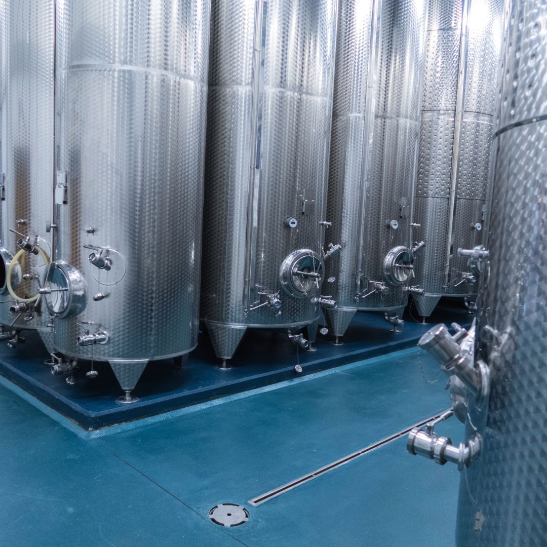A row of stainless steel tanks are lined up in a room.