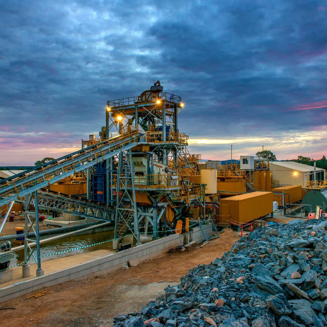 A mining site with a lot of machinery and a pile of rocks in the foreground