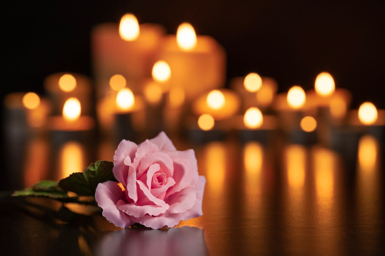 Pink rose laying in front of lite candles