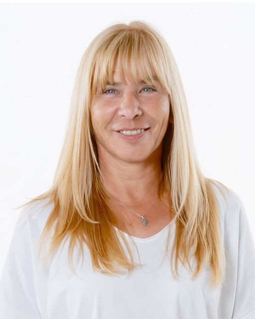 Eine Frau in einem weißen Hemd lächelt vor einem grünen Hintergrund.