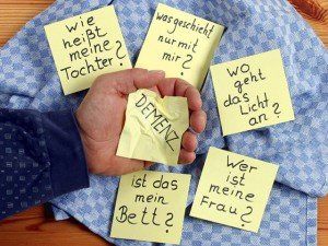 Eine Hand hält ein Stück Papier mit der Aufschrift „Demenz“.
