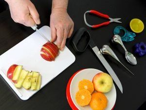 Eine Person schneidet einen Apfel auf einem Schneidebrett