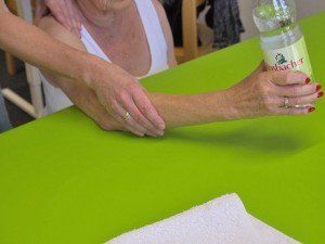 Eine Frau sitzt an einem Tisch und hält eine Flasche Wasser in der Hand.