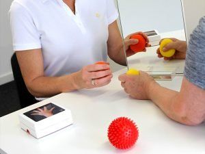 Eine Frau und ein Mann sitzen an einem Tisch und spielen vor einem Spiegel mit Bällen.