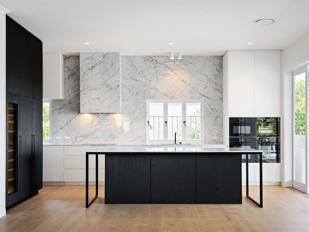 A Kitchen With a Black Island and White Cabinets — Hot Rock Granite In Byron Bay, NSW