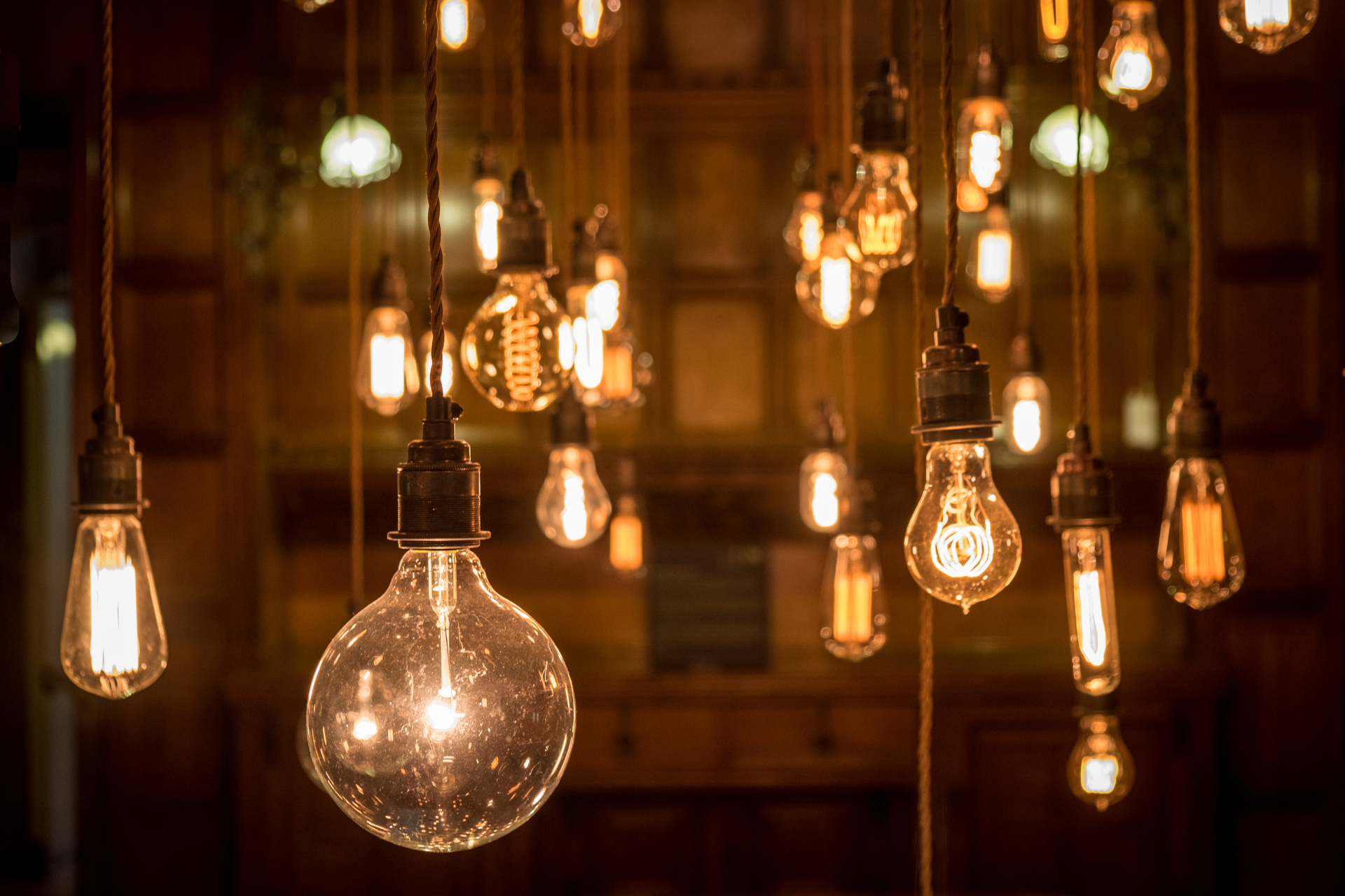 a bunch of light bulbs hanging from the ceiling in a dark room .