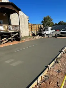 Freshly poured concrete driveway under construction next to a building.