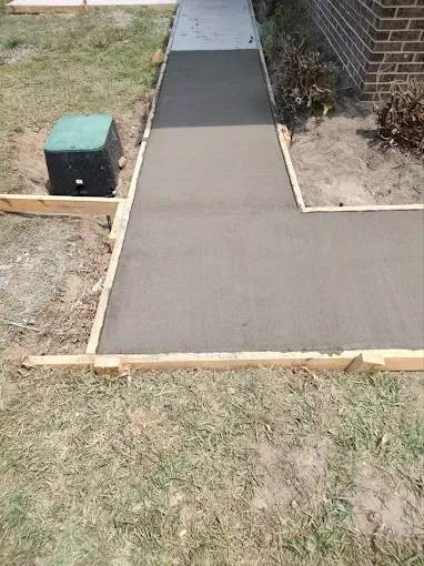 Newly poured concrete walkway with wooden forms.