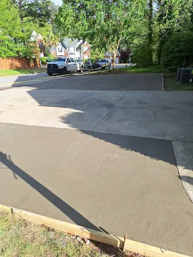Newly paved concrete driveway with parked vehicles in a residential neighborhood.