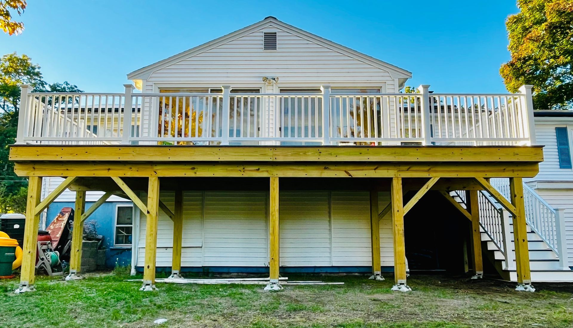 A large, elevated wooden deck with white railings attached to the back of a house.