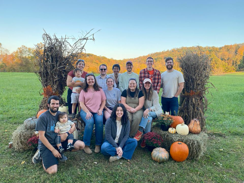 A group of people are posing for a picture in a field with pumpkins.