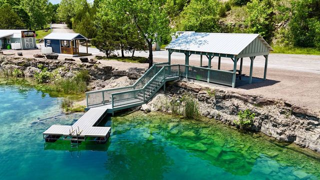 Lakeside dock with stairs and a covered pavilion over clear turquoise water