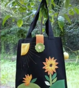 una borsa di color nero con dei disegni dei fiori arancioni