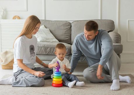 A family is sitting on the floor playing with toys.