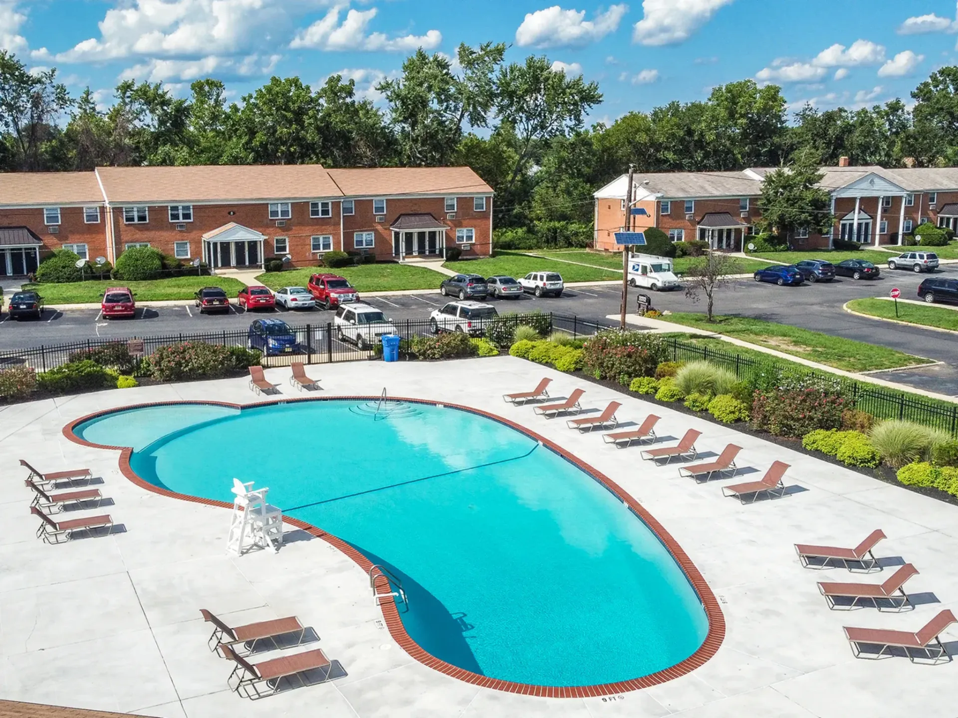 Aerial view of a resort-style outdoor pool with lounge chairs at an apartment community.