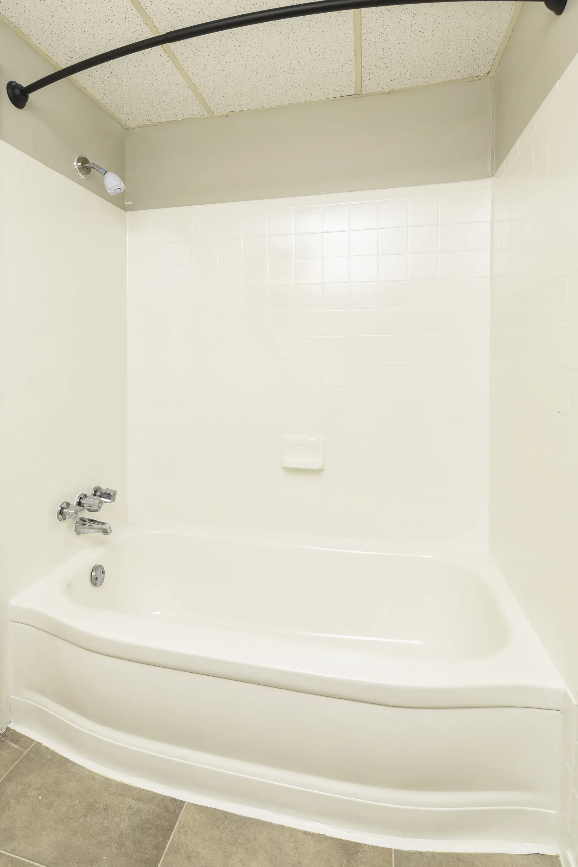 White bathtub with tiled walls and a curved shower rod in a small apartment bathroom.