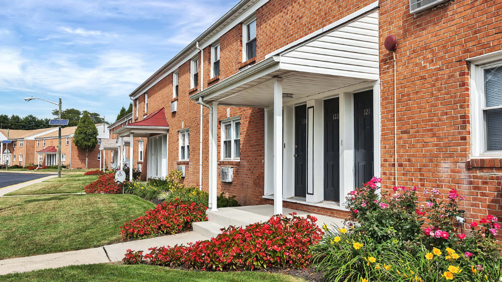 Brick apartment building with landscaped entrances and colorful flowers.
