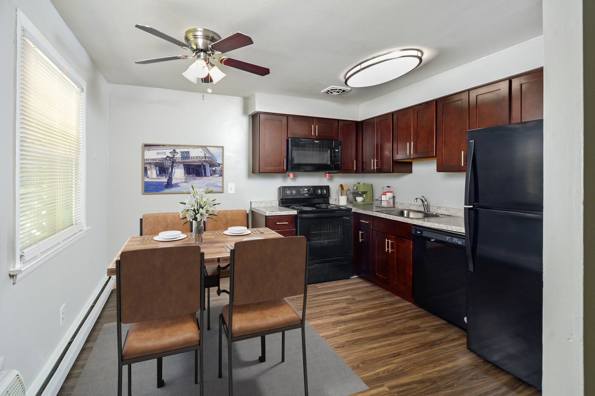 Interior of an apartment kitchen with dark wood cabinets and a dining table.
