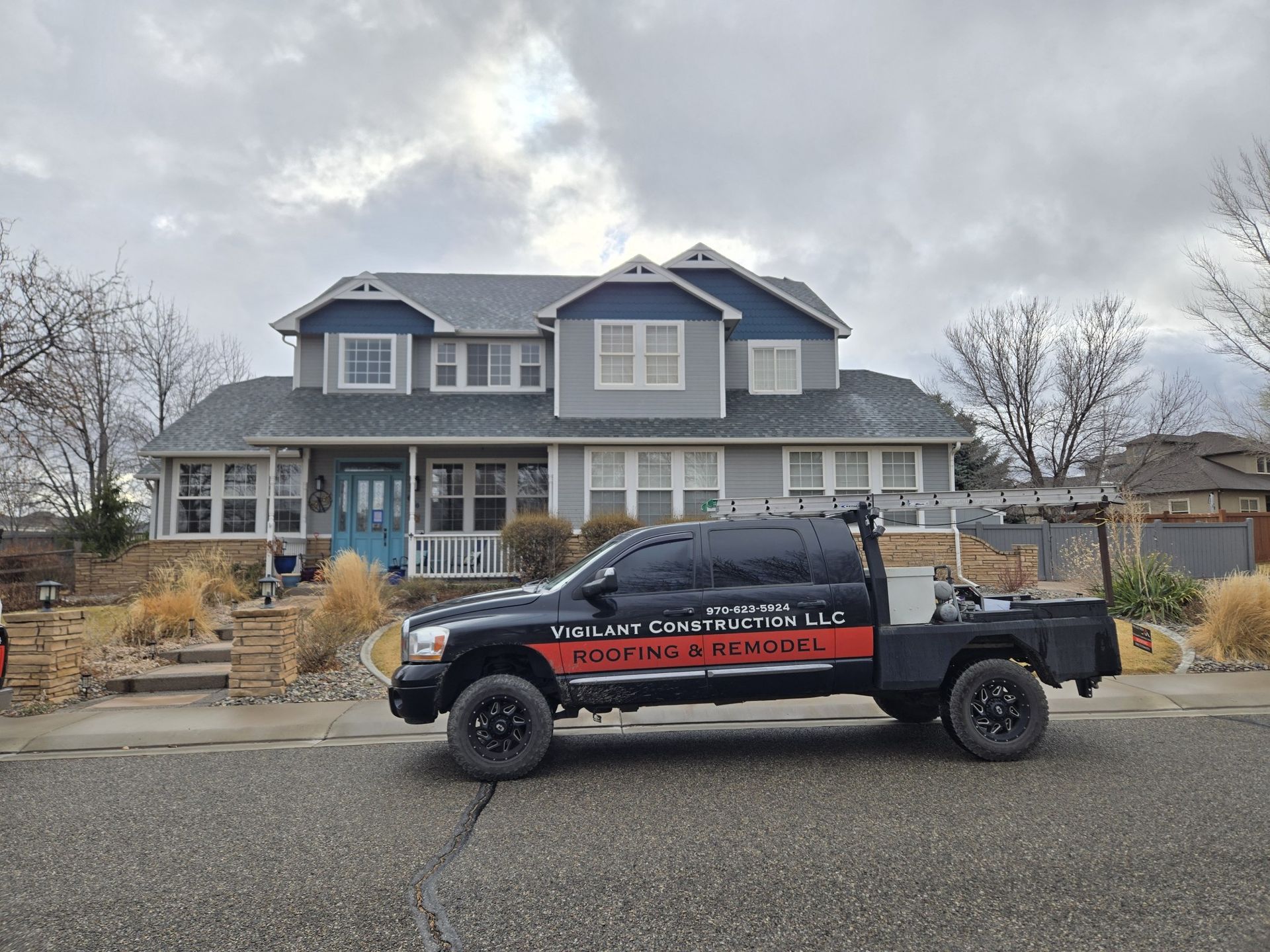 A black truck is parked in front of a large house.