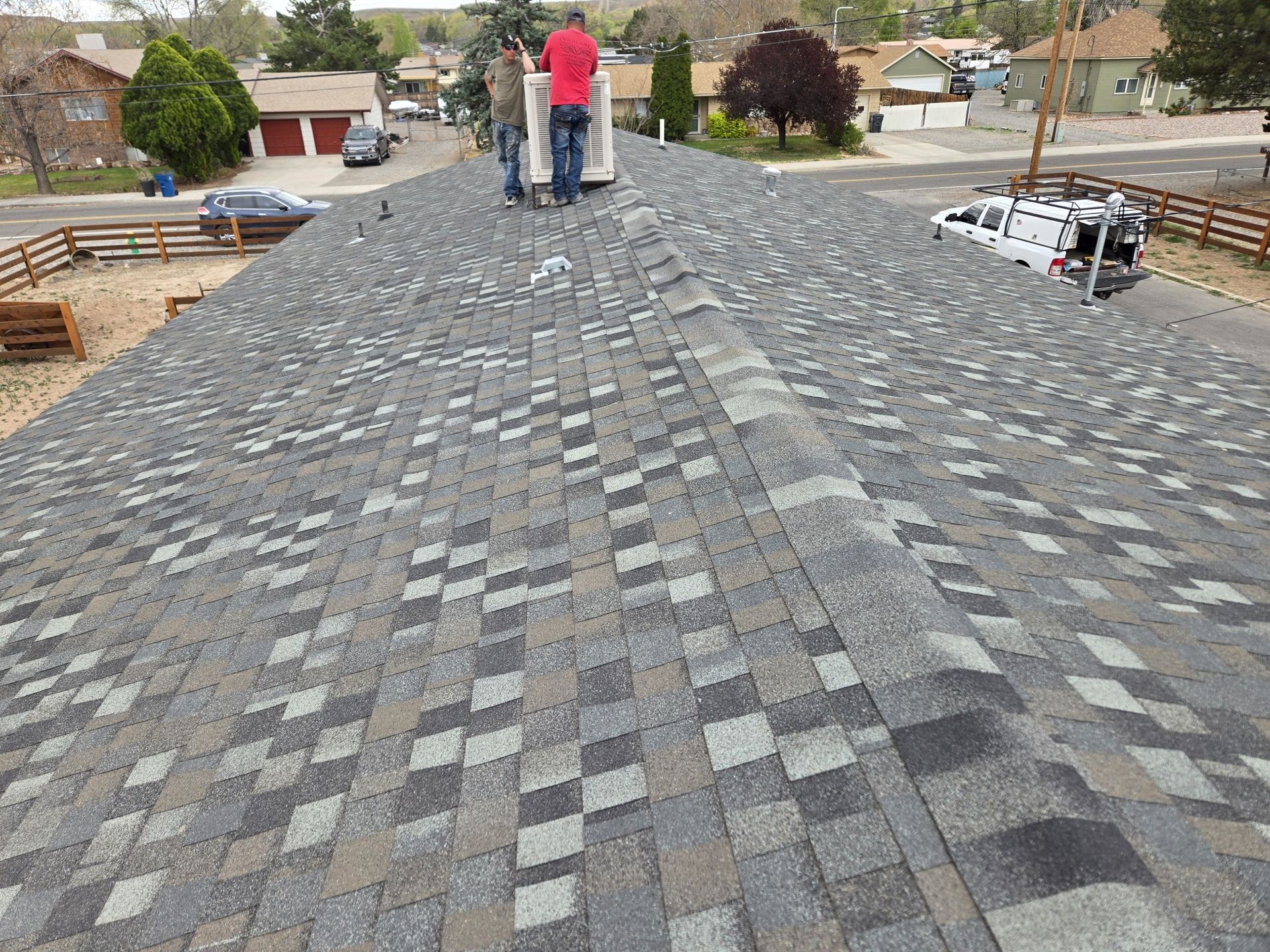 A man in a red shirt is standing on top of a roof.