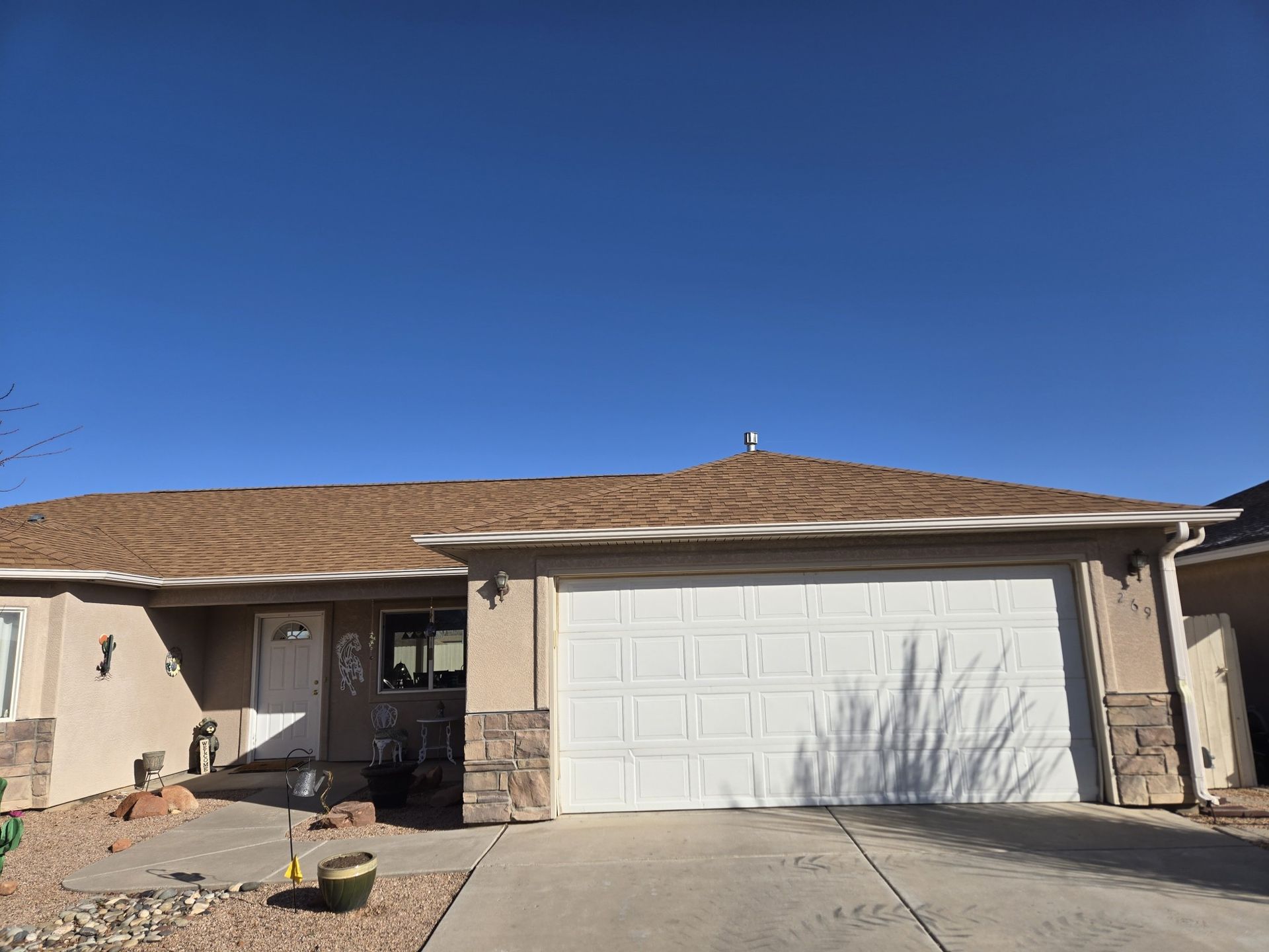 A house with a white garage door and a blue sky in the background.