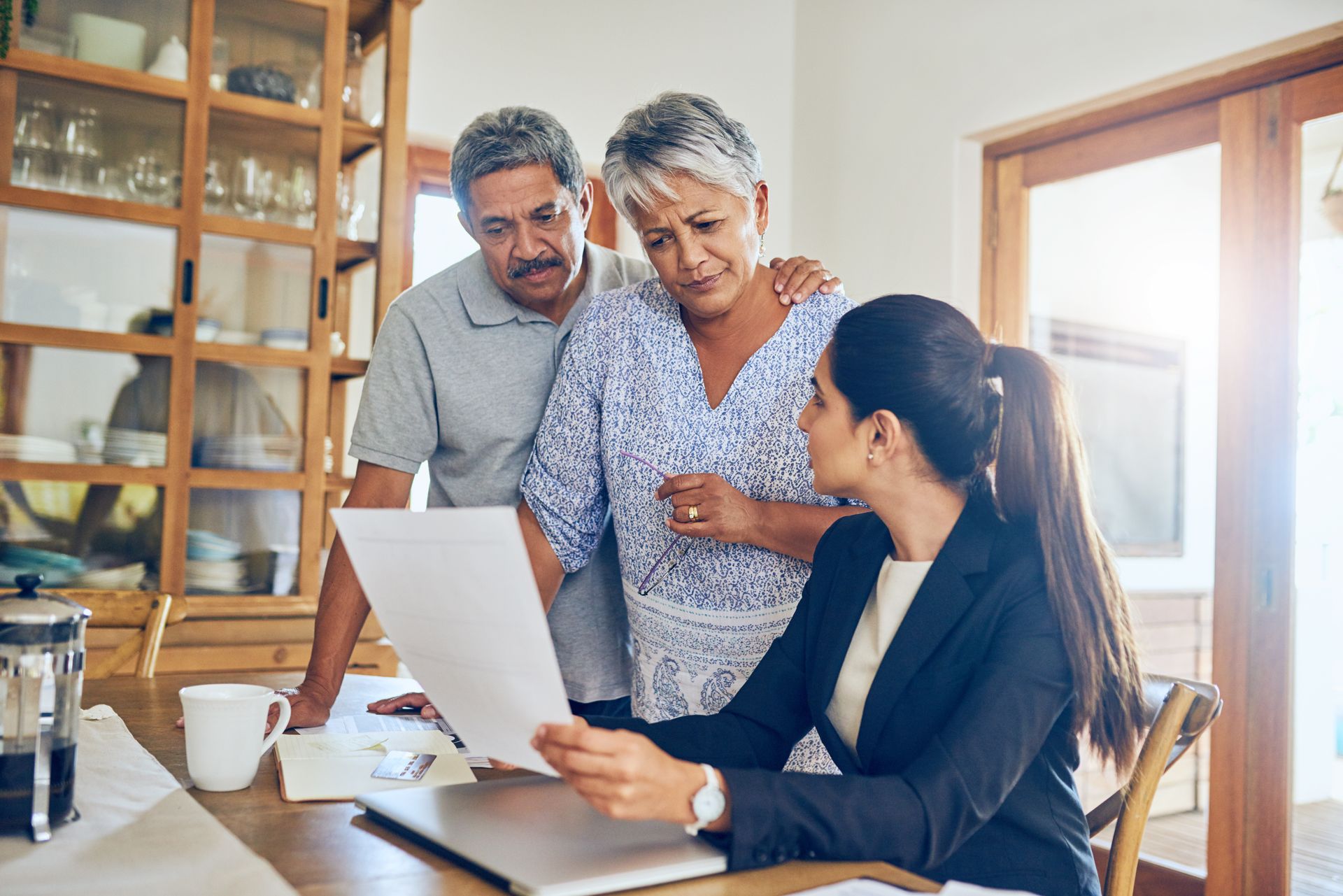 Estate planner reviews documents with a couple gathered around a table in a bright home office.
