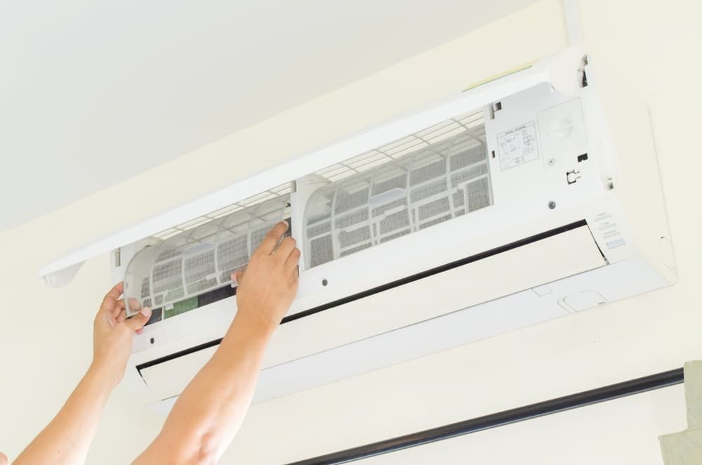 Hands Are Adjusting the Filter Inside an Open Wall-mounted Air Conditioning Unit