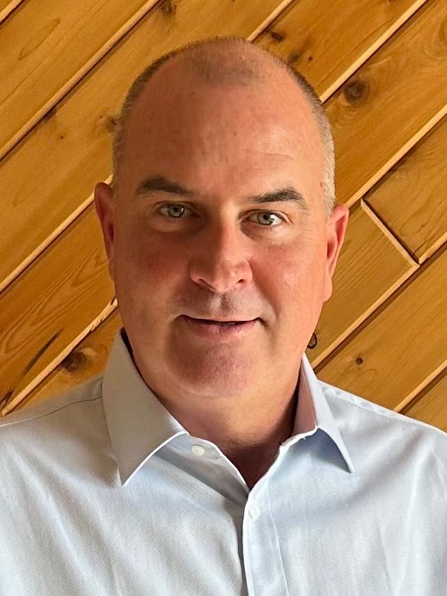 Silhouette of a man with arms crossed. He is against a light gray background.