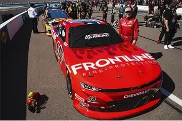 Red Frontline Chevrolet race car in pit lane with crew members nearby