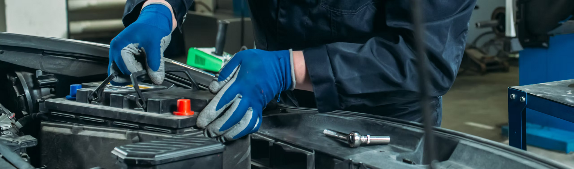 A man is working on a car battery in a garage.