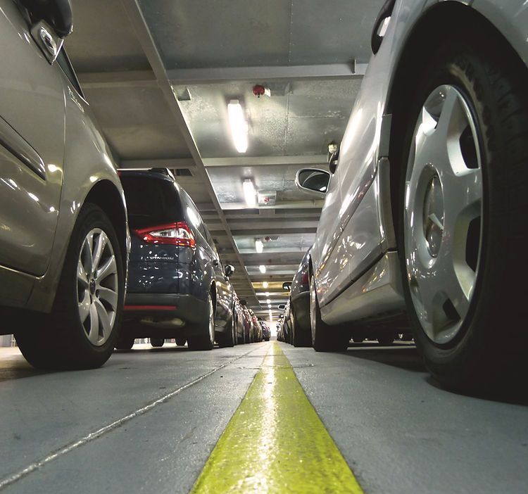 A row of cars are parked in a parking garage
